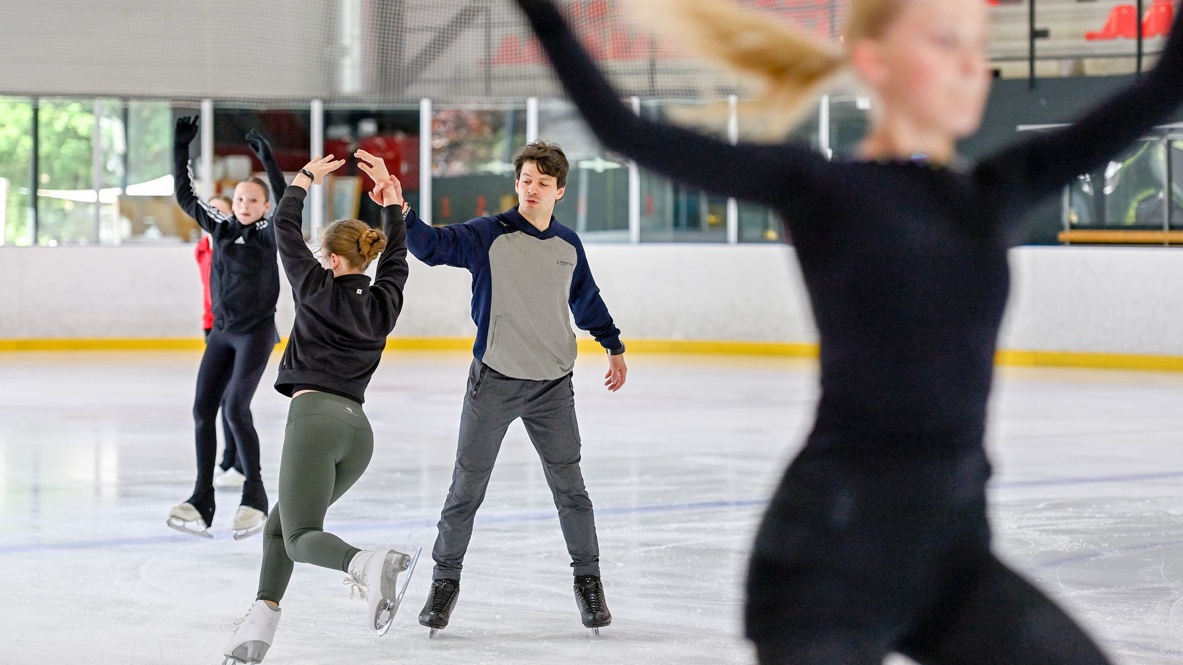 A coach demonstrating an arm position to skaters training on the ice at the Palladium de Champéry.